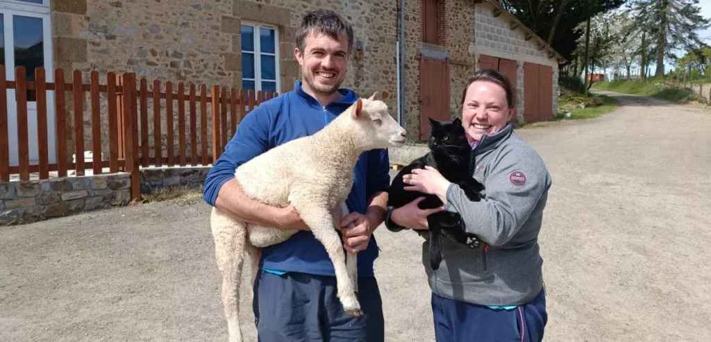 Mathieu avec un agneau dans les bras et Mélanie portant son chat à la ferme Les Berges Rien à Chailland en Mayenne